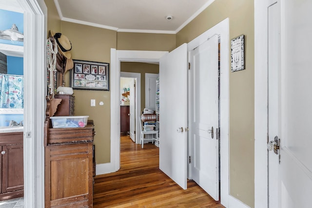 corridor with sink, light hardwood / wood-style flooring, and ornamental molding