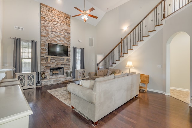 living room featuring ceiling fan, a fireplace, high vaulted ceiling, and dark wood-type flooring