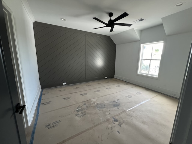 unfurnished room featuring ceiling fan, lofted ceiling, and wooden walls