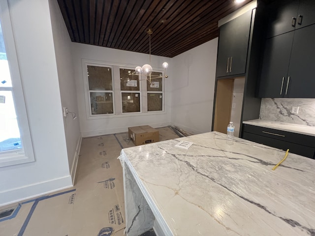 kitchen with tasteful backsplash, decorative light fixtures, a chandelier, and light stone countertops