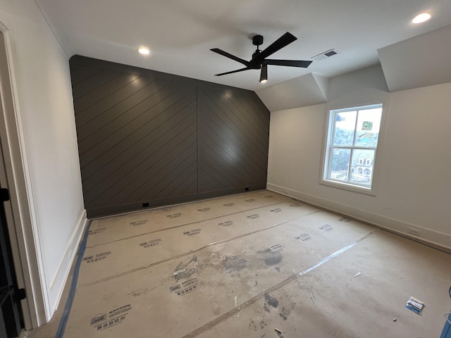 interior space with lofted ceiling, wooden walls, and ceiling fan