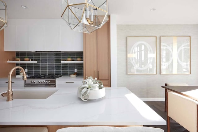 kitchen featuring pendant lighting, dark wood-type flooring, light stone counters, and backsplash