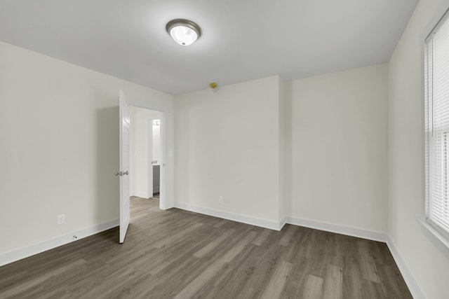 spare room with dark hardwood / wood-style floors and plenty of natural light