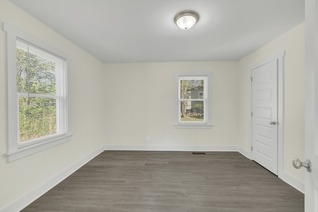 empty room with a wealth of natural light and dark hardwood / wood-style floors