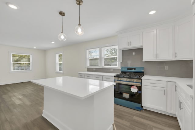 kitchen featuring white cabinets, stainless steel gas range, light hardwood / wood-style flooring, and tasteful backsplash