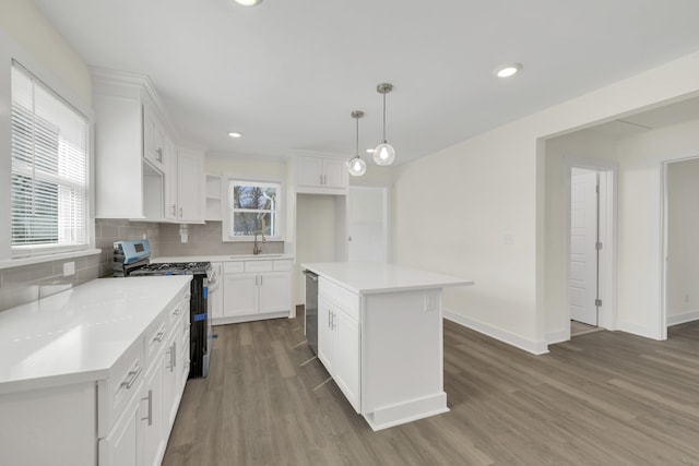 kitchen featuring gas stove, white cabinetry, decorative light fixtures, dark wood-type flooring, and a center island