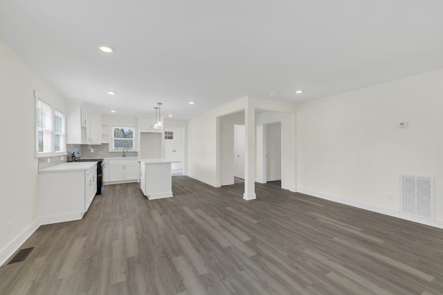 kitchen featuring white cabinetry, decorative light fixtures, a center island, dark wood-type flooring, and electric stove