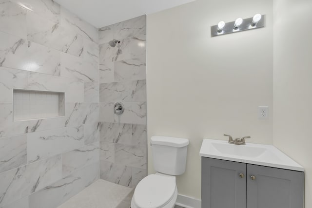 bathroom featuring vanity, toilet, and tiled shower