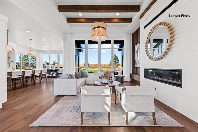 living room featuring dark hardwood / wood-style floors, beam ceiling, and a large fireplace