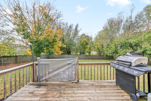 wooden deck with a yard and a grill