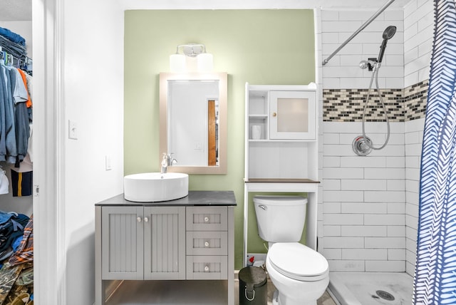 bathroom with tiled shower, toilet, and vanity