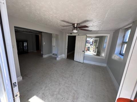 interior space with ceiling fan, carpet, and a textured ceiling