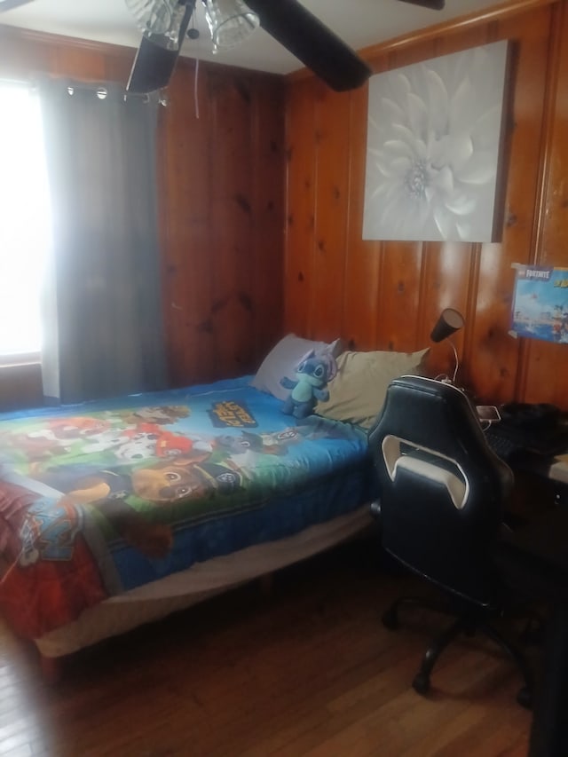 bedroom with hardwood / wood-style floors, wooden walls, and ceiling fan