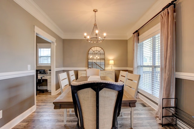 dining room with ornamental molding, hardwood / wood-style floors, and a notable chandelier