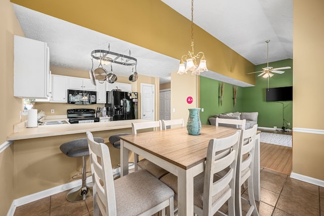 tiled dining area featuring ceiling fan with notable chandelier and sink