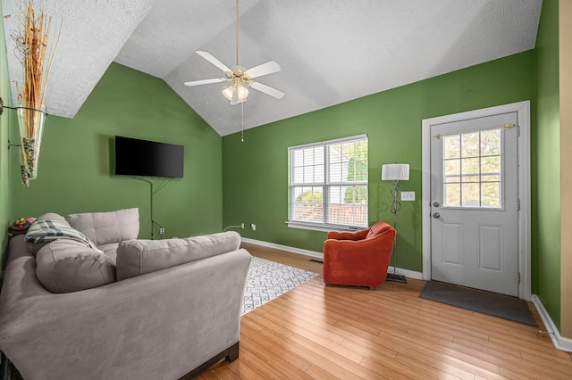 living room featuring light hardwood / wood-style flooring, lofted ceiling, and a textured ceiling