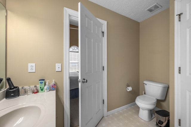 bathroom featuring vanity, a textured ceiling, and toilet