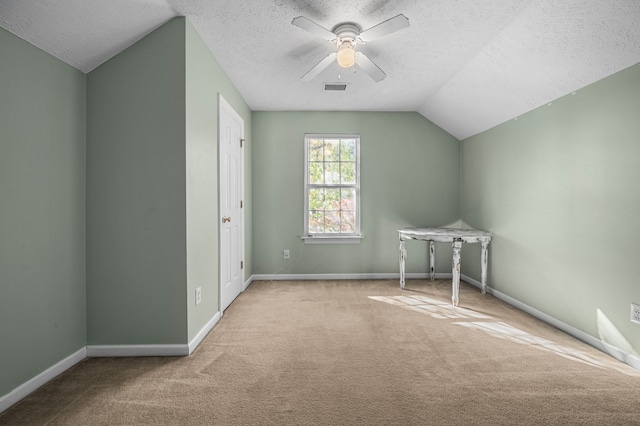 additional living space with a textured ceiling, lofted ceiling, light carpet, and ceiling fan