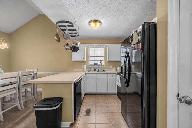 kitchen with white cabinetry, sink, black appliances, light tile patterned floors, and lofted ceiling