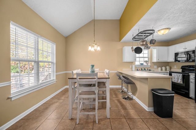 kitchen with black appliances, white cabinetry, a healthy amount of sunlight, and a breakfast bar