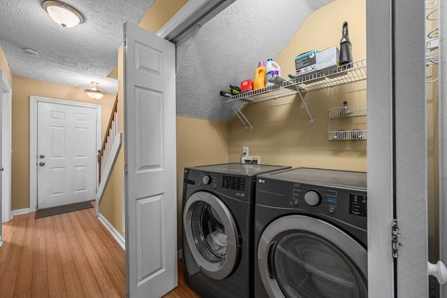 washroom with light hardwood / wood-style floors, washing machine and dryer, and a textured ceiling