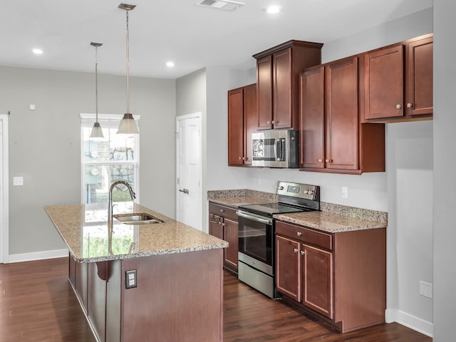 kitchen featuring stainless steel appliances, sink, an island with sink, dark hardwood / wood-style floors, and decorative light fixtures