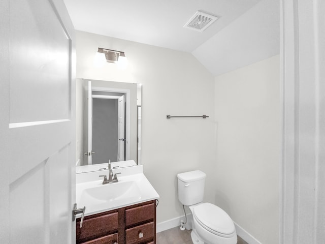 bathroom with vanity, toilet, and lofted ceiling