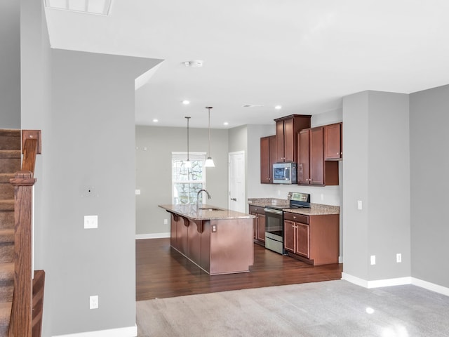 kitchen featuring stainless steel appliances, pendant lighting, sink, a kitchen breakfast bar, and a kitchen island with sink