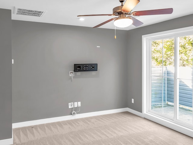 unfurnished room featuring ceiling fan, a wealth of natural light, and light colored carpet