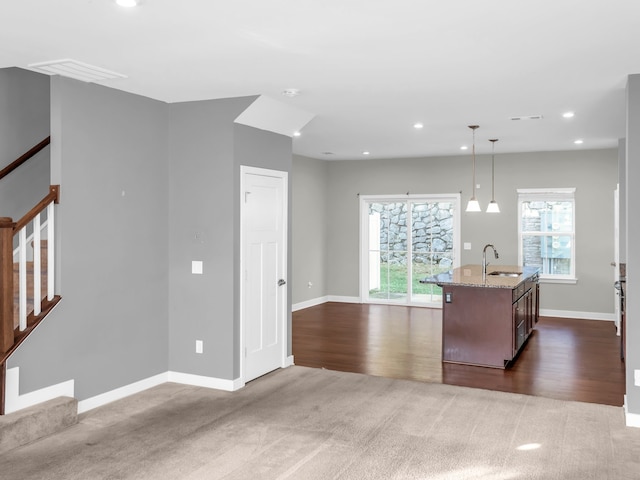 kitchen with pendant lighting, dark wood-type flooring, sink, and light stone counters