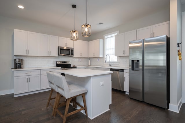 kitchen with dark hardwood / wood-style floors, white cabinetry, appliances with stainless steel finishes, and a center island