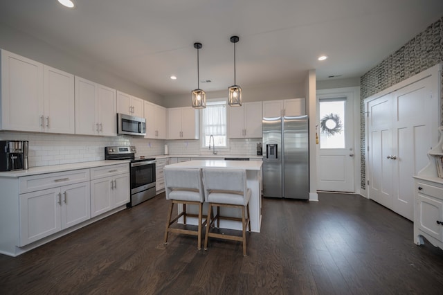 kitchen featuring stainless steel appliances, dark hardwood / wood-style flooring, a breakfast bar, white cabinets, and a center island