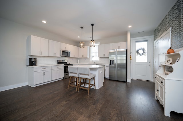 kitchen with white cabinets, stainless steel appliances, pendant lighting, and a center island