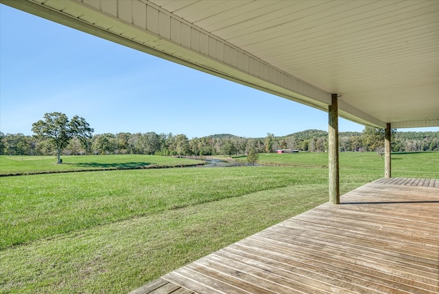 wooden terrace with a rural view and a lawn