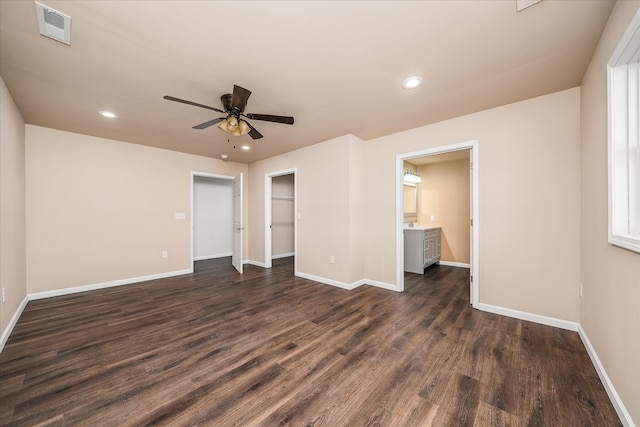 unfurnished bedroom with ensuite bath, dark wood-type flooring, ceiling fan, and a closet