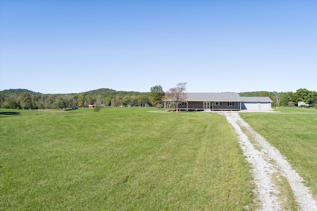 view of yard featuring a garage, a mountain view, and a rural view