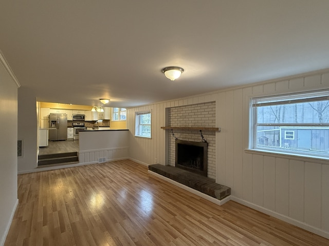 unfurnished living room featuring a fireplace, crown molding, and light hardwood / wood-style flooring