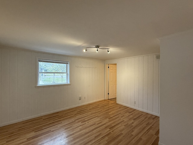 spare room with wood walls and light wood-type flooring