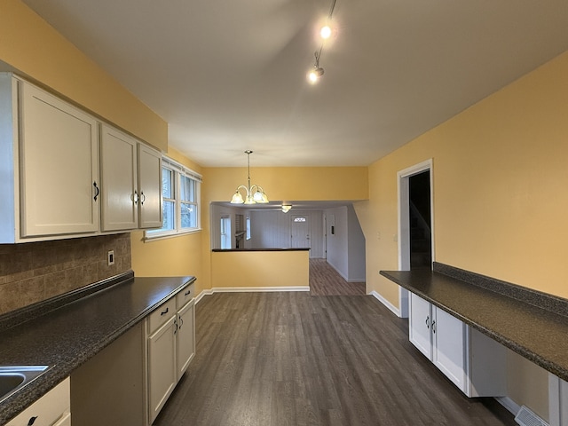 kitchen with white cabinets, a notable chandelier, dark hardwood / wood-style floors, backsplash, and pendant lighting