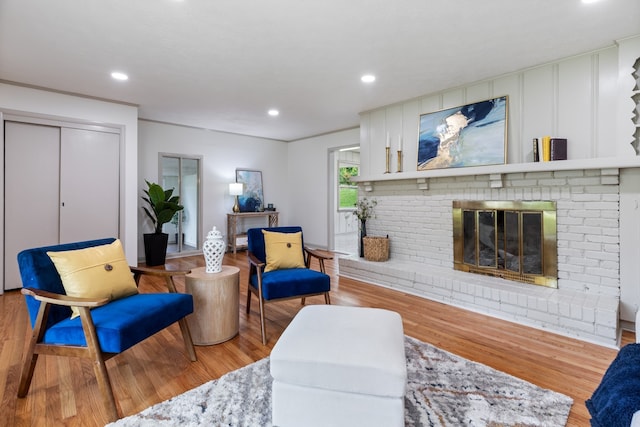 living room featuring a brick fireplace and light wood-type flooring