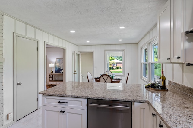 kitchen with white cabinets, ornamental molding, a textured ceiling, and light stone countertops