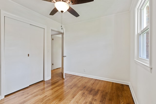 unfurnished bedroom with ceiling fan, a closet, light wood-type flooring, and ornamental molding