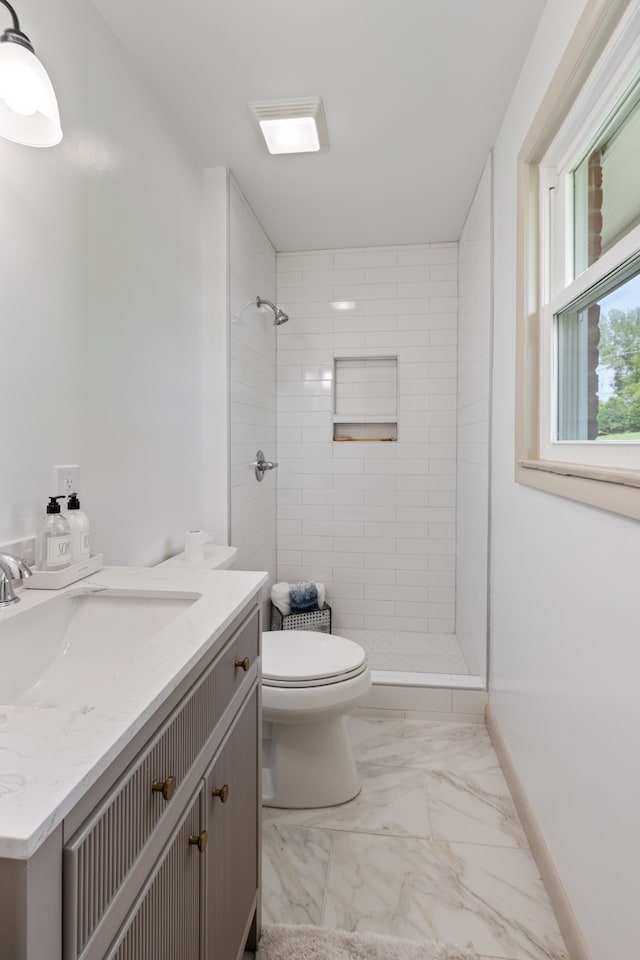 bathroom with toilet, vanity, and tiled shower