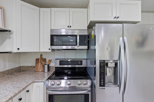 kitchen with white cabinetry, appliances with stainless steel finishes, a textured ceiling, and light stone countertops