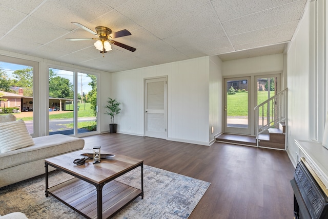 living room featuring ceiling fan, a paneled ceiling, and dark hardwood / wood-style flooring