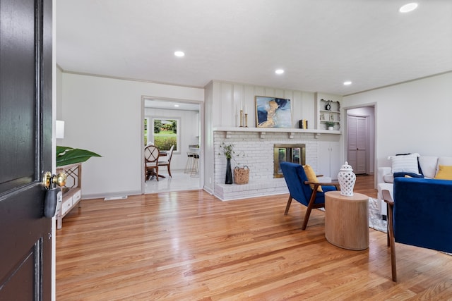 living room featuring a brick fireplace and light hardwood / wood-style flooring