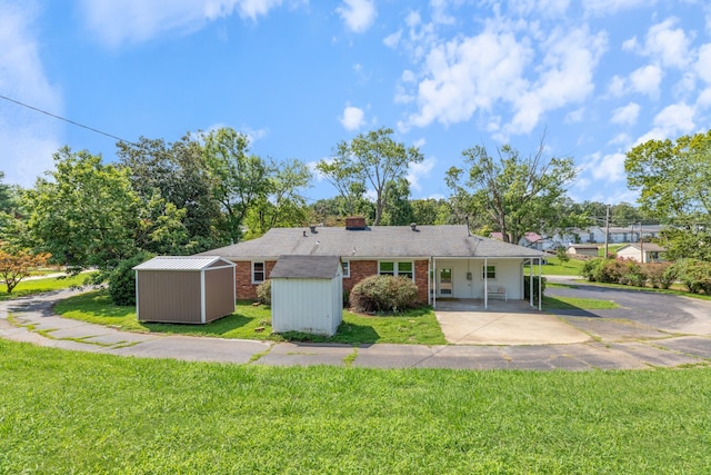 back of house with a storage unit and a yard