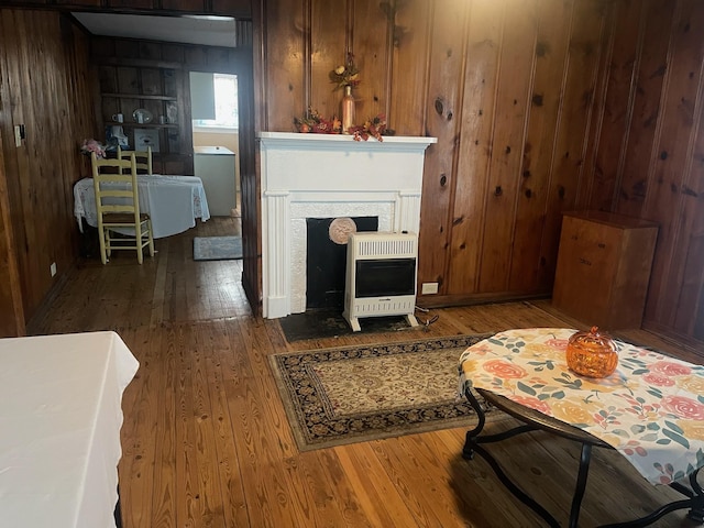 living room with heating unit, wood walls, and dark hardwood / wood-style flooring