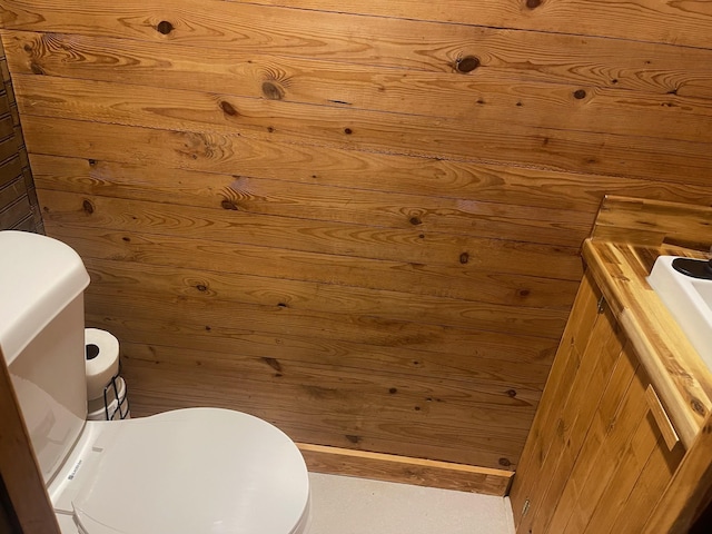 bathroom featuring vanity, toilet, and wooden walls