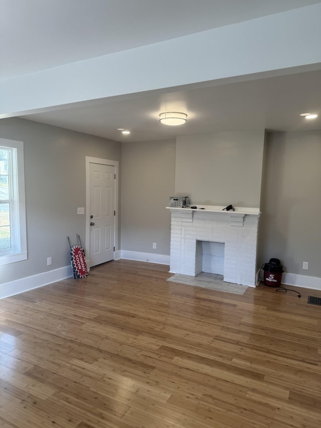 unfurnished living room featuring wood-type flooring and a fireplace